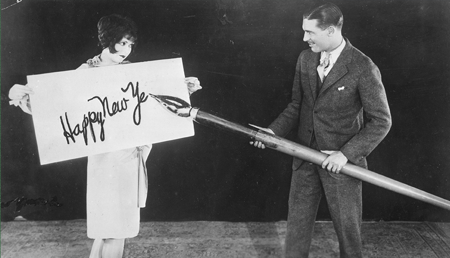 A man writing “Happy New Year’s” on a big piece of cardboard.