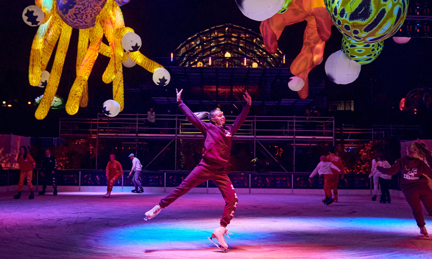 The Rink at Rising Melbourne offers a place to go ice skating in the city centre. Image shows a woman junping on the ice in ice skates.