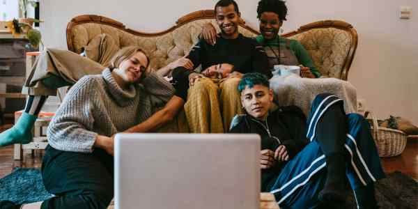 Happy group of friends watching something on a laptop.