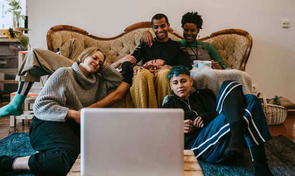 Happy group of friends watching something on a laptop.