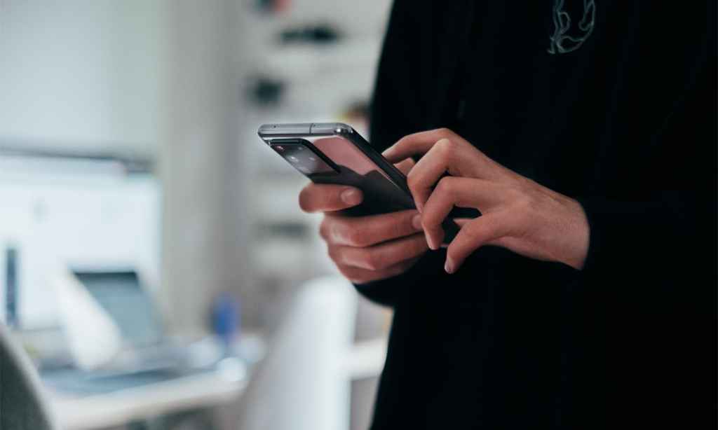 Close-up of someone in a black jumper using a phone.