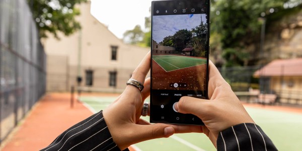 Feminine hands taking a photo of a basketball court with the Samsung Galaxy S23 Ultra.