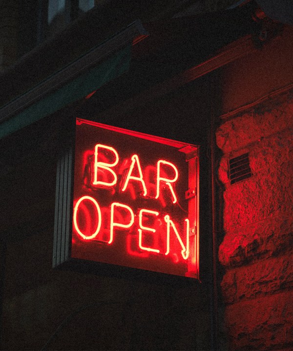 A red glowing neon sign reading 'bar open' to indicate venues and pubs that can survive without pokies.