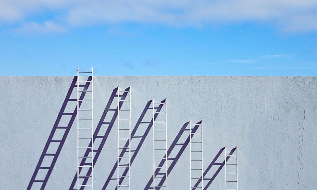 An image showing increasingly small ladders reaching up to the same height to indicate the impact of inflation on wages.